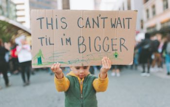 A little boy holding up a sign at a climate change rally.